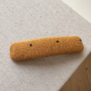 Detailed macro view of yellow knitted hair clip with black polka dots on linen fabric