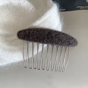 Detail of dark grey felt hair comb with 10 silver metal teeth on white mohair fabric