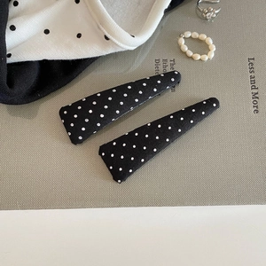 Detail of two black polka dot fabric hair clips with a vintage French style design