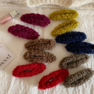 Colorful plush BB hair clips in autumn winter shades on a soft white knit background