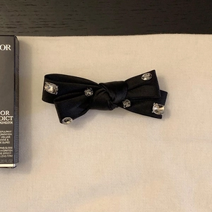 Détail d'une barrette à cheveux nœud en satin noir ornée de cinq strass brillants incrustés