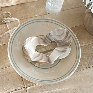 Detailed view of cream marble heart-shaped claw clip on elegant ceramic dish