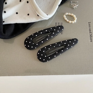 Close-up of black and white polka dot fabric BB hair clips with classic metal structure