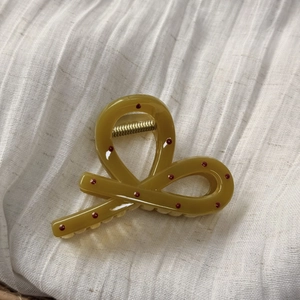 Détail de la pince à cheveux jaune moutarde à pois avec ressort en métal doré