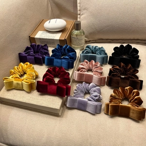 Elegant multi-color velvet double bow hair scrunchies displayed in a cozy home setting