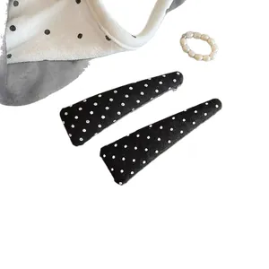 Pair of Korean style black fabric hair clips with white polka dot pattern on white background