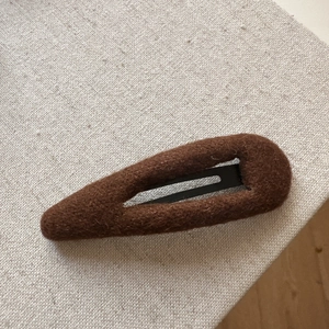 Brown knit hair clip for women featuring textured plush fabric on a rustic grey background