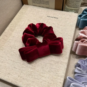 Detail showing high-quality burgundy velvet double-layer bow scrunchie on a decorative book
