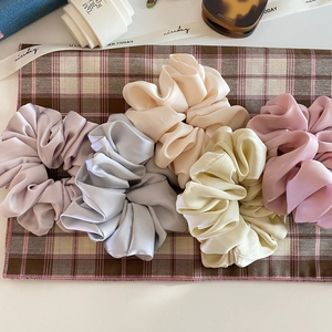 French cream satin scrunchies in pastel colors on a stylish plaid background decor