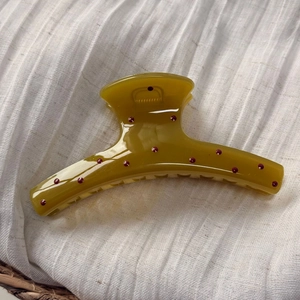 Pince à cheveux jaune moutarde à pois rouges sur fond de tissu texturé blanc
