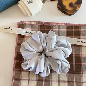Close-up of silk satin scrunchie texture with soft grey sheen and elegant pleats