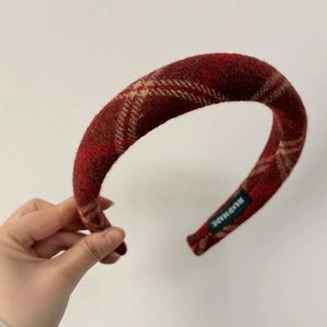 Close-up of thick red plaid headband fabric with a green Handmade label inside