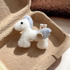 Macro detail of wool felt horse brooch with wood button and red H label on a pulp tray