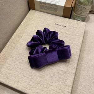 Detail of premium purple velvet scrunchie with a double-layered bow on a beige stand