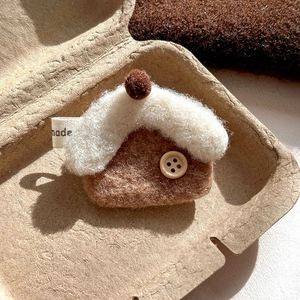 Close-up of handmade red horse brooch with wool felt texture and wooden button detail