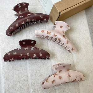 Pink and brown butterfly hair claws in set of four on light textured stone surface