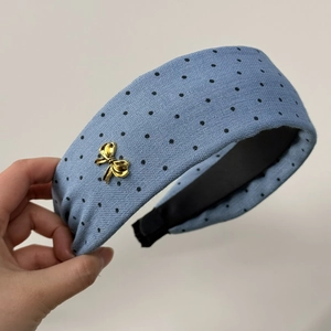 Dettaglio del cerchietto blu a pois neri con fiocco dorato e fodera interna morbida