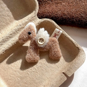 Detail of handmade brown plush pony brooch with white felt wings and button accent