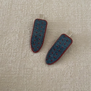 Detail of blue denim hair clips with red polka dots and metal grip on beige fabric