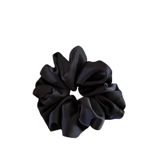 Minimalist black satin scrunchie with elegant pleated fabric design and elastic structure