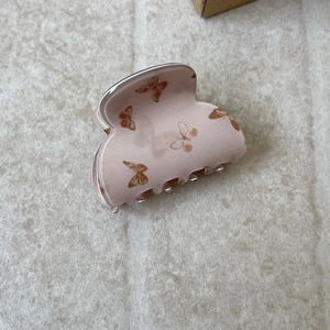 Close-up of translucent pink hair claw clip with vintage brown butterfly patterns