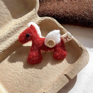 Detailed view of handmade red wool felt pony brooch with white wings and wood button