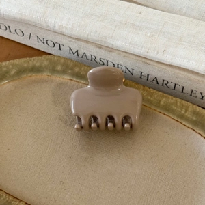 Detail einer beige glänzenden Haarklammer aus Harz auf einer Keramikschale für Damen