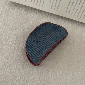 Detail of blue denim fabric textured hair claw with red polka dots and wine red plastic teeth