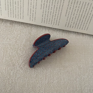 Detailed view of large retro denim blue hair claw clip with red polka dots on an open book