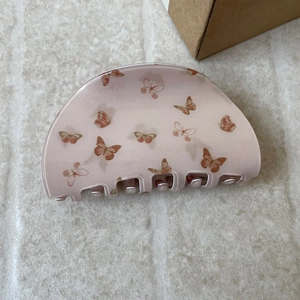 Detailed view of large pink butterfly hair claw clip with brown patterns on stone surface