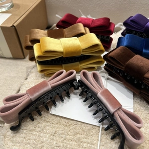 Elegant velvet double bow banana hair clips in multiple colors on a textured fabric