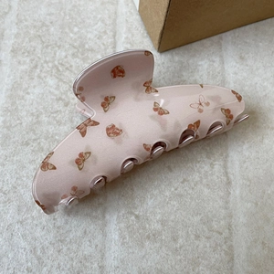 Detail of pink translucent hair claw clip with elegant brown butterfly patterns
