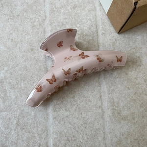 Close-up of large pink hair claw clip featuring vintage brown butterfly patterns