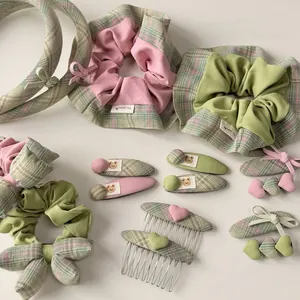 Details von rosa und grünem Haarschmuck-Set mit Karomuster, Haargummis und Bären-Clips