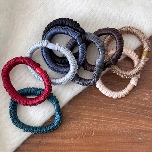 High-elastic silk satin hair scrunchies set in various colors on a soft knit background
