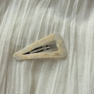 Detail of triangle acetate hair clip featuring cream marble texture and silver metal base
