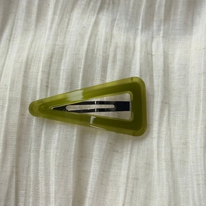 Detail of olive green acetate triangle hair clip showing silver metal snap closure