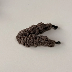 Close-up of dark brown knitted banana clip hair accessory with spiral wavy texture