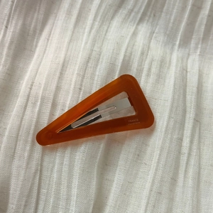 Detail of triangle acetate hair clip showing the France Handmade logo on amber resin