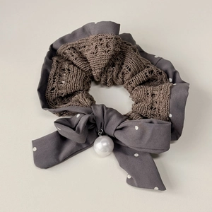 Detail of knitted polka dot scrunchie with a bow and elegant faux pearl pendant