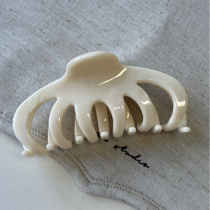 Macro detail of creamy beige marble textured acetate hair claw clip with glossy finish