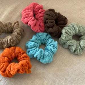 Set of six colorful knit scrunchies in orange, pink, blue, and brown on beige linen
