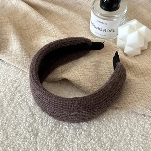 Detailed close-up of dark brown knitted wide headband texture with soft plush background