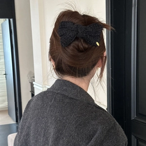 Elegant black tweed bow hair clip with gold metal accent on woman's updo hairstyle