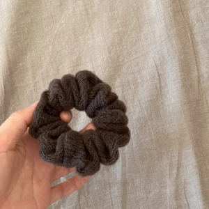 Macro detail of dark brown knitted scrunchie showing thick yarn texture and soft autumn style