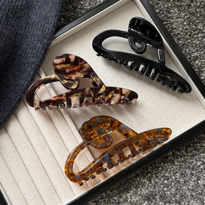 Three-piece set of large heart cutout hair claws in black, tortoiseshell, and marble finishes