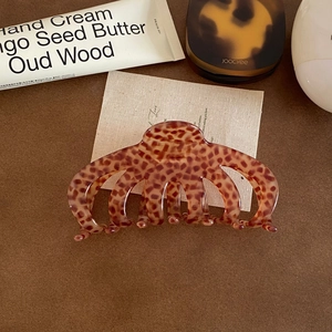 Close-up of tortoise shell pattern large acetate hair claw clip on leather surface