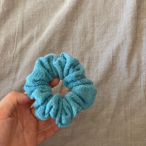 Detail of light blue knitted hair scrunchie with soft ribbed texture and wool material