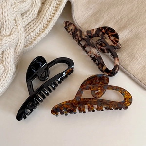 Three large tortoiseshell and black acetate hollow heart hair claws on knit sweater