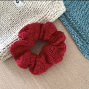 Close-up of a red knitted mohair hair scrunchie with soft texture on wooden background